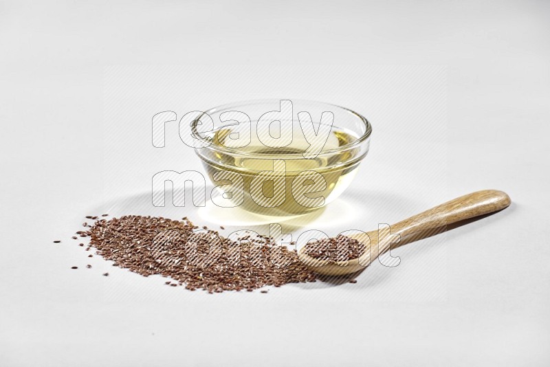 A glass bowl full of flax oil and wooden spoon full of flax seeds spreaded on a white flooring in different angles