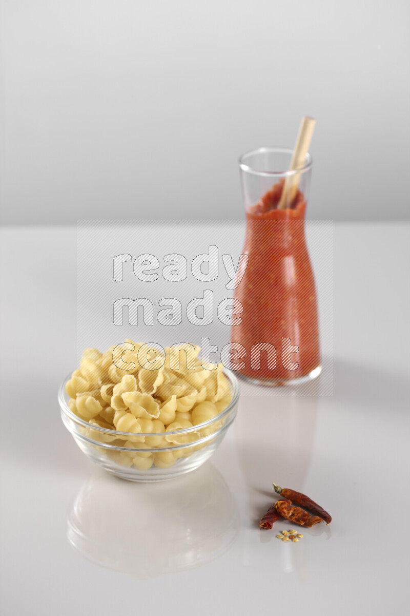 معكرونة مع صلصة طماطم مع مكونات متنوعة من الطماطم والثوم والريحان والفلفل الأحمر والفلفل الأسود والفلفل الأبيض وأوراق الغار والهيل وسنابل القمح على خلفية رمادية