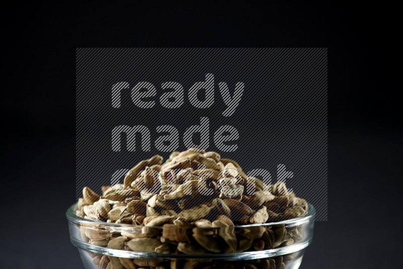 A glass bowl full of cardamom on black flooring