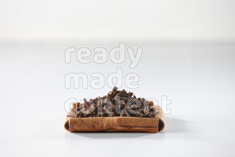 A single square of cinnamon sticks full of cloves on white flooring