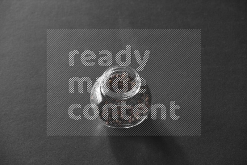 فلفل أسود في وعاء زجاجي علي خلفية سوداء