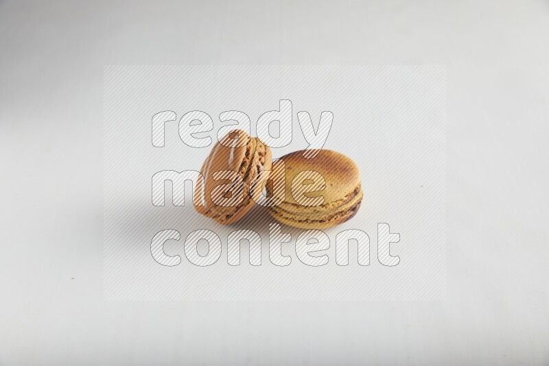 45º Shot of of two assorted Brown Irish Cream, and Yellow Crème Brulée macarons on white background