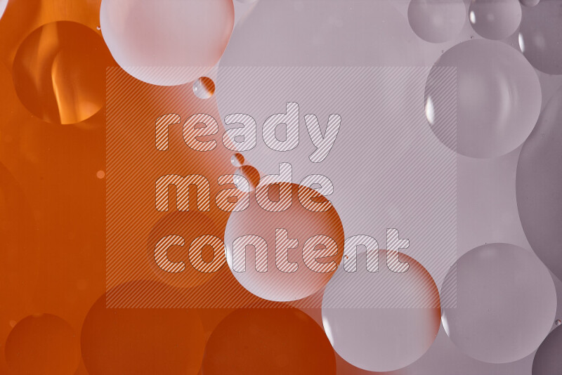 Close-ups of abstract oil bubbles on water surface in shades of white and orange