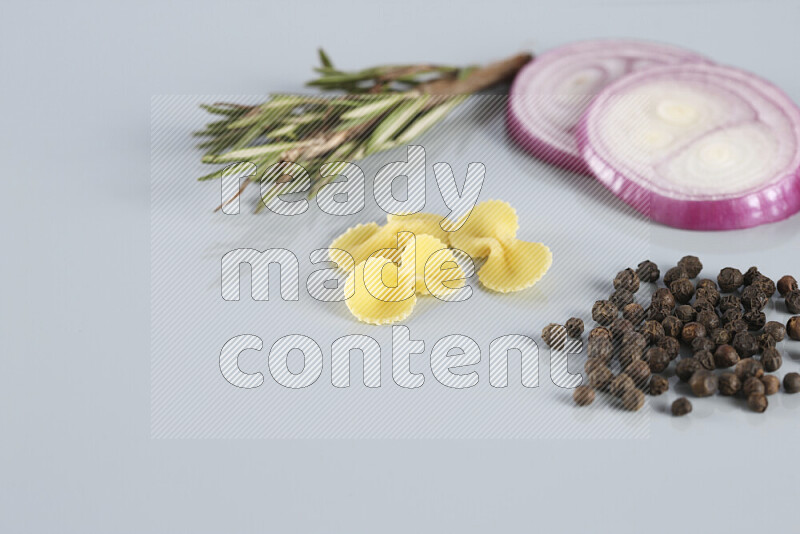 Raw pasta with different ingredients such as cherry tomatoes, garlic, onions, red chilis, black pepper, white pepper, bay laurel leaves, rosemary, cardamom and mushrooms on light blue background