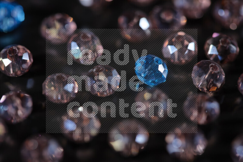 Rose and blue transparent crystal beads scattered on a black background