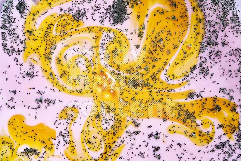 لقطة مقربة لبريق أخضر متلألئ منتشر على خلفية من اللون الأصفر والوردي في حركات دائرية