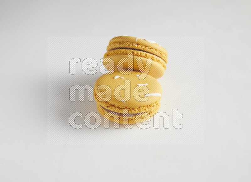 45º Shot of two Yellow Piña Colada macarons on white background