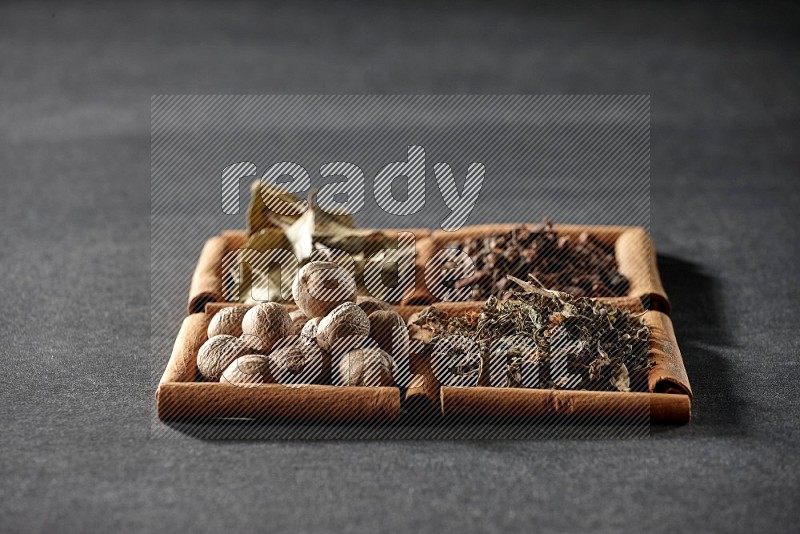 4 squares of cinnamon sticks full of bay laurel leaves, dried basil, cloves and nutmegs on black flooring
