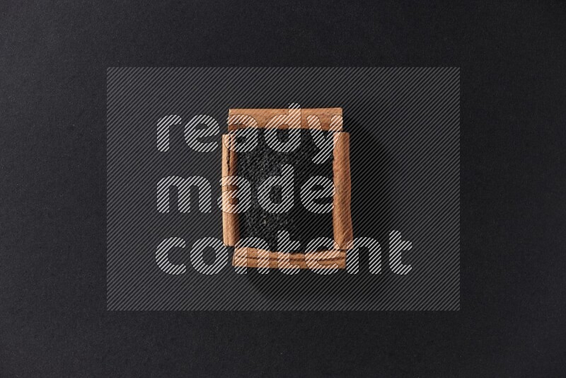 A single square of cinnamon sticks full of black seeds on black flooring