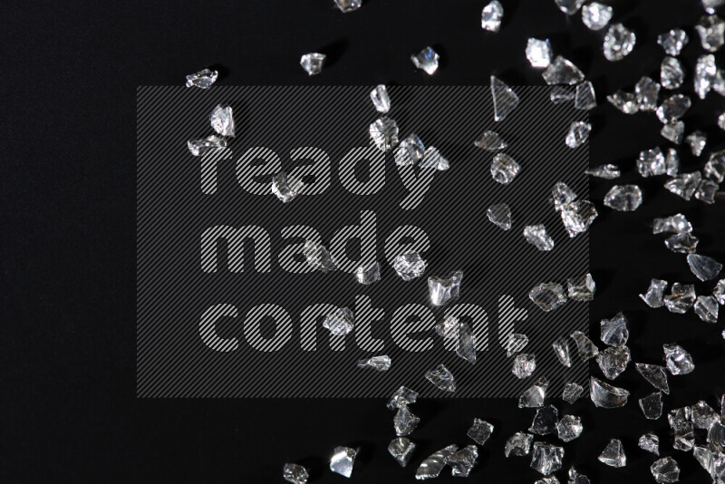 قطع زجاجية فضية لامعة متناثرة على خلفية سوداء