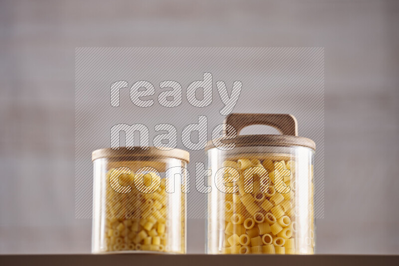 Raw pasta in glass jars on beige background