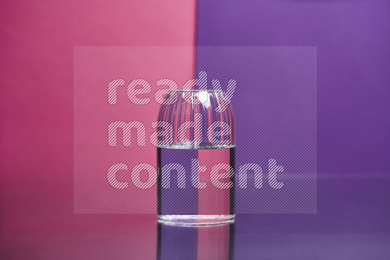 The image features a clear glassware filled with water set against pink and purple background