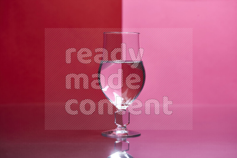 The image features a clear glassware filled with water, set against red and pink background