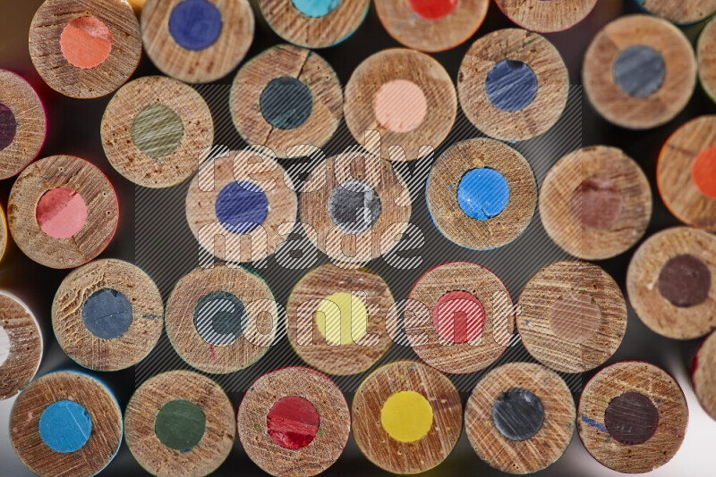 A close-up of the tips of colored pencils arranged in a bundle on white background