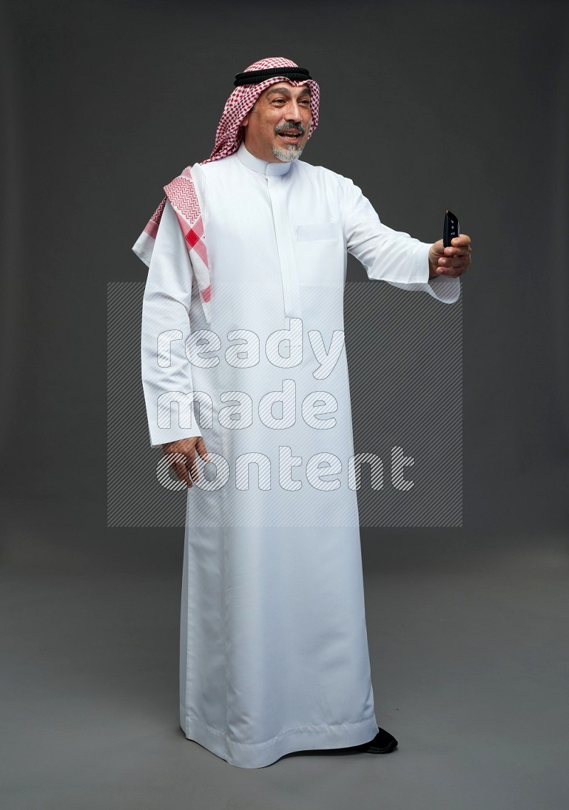 Saudi man with shomag Standing holding car key on gray background