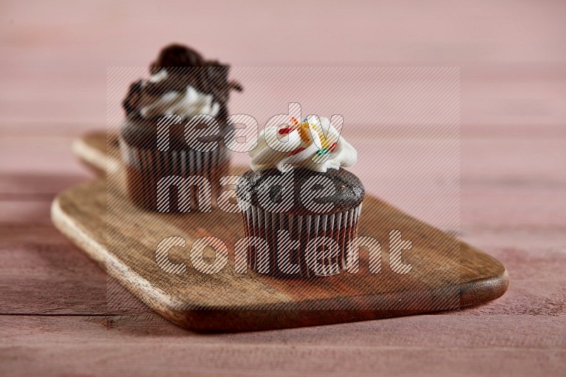 Chocolate mini cupcake topped with cream on a wooden board