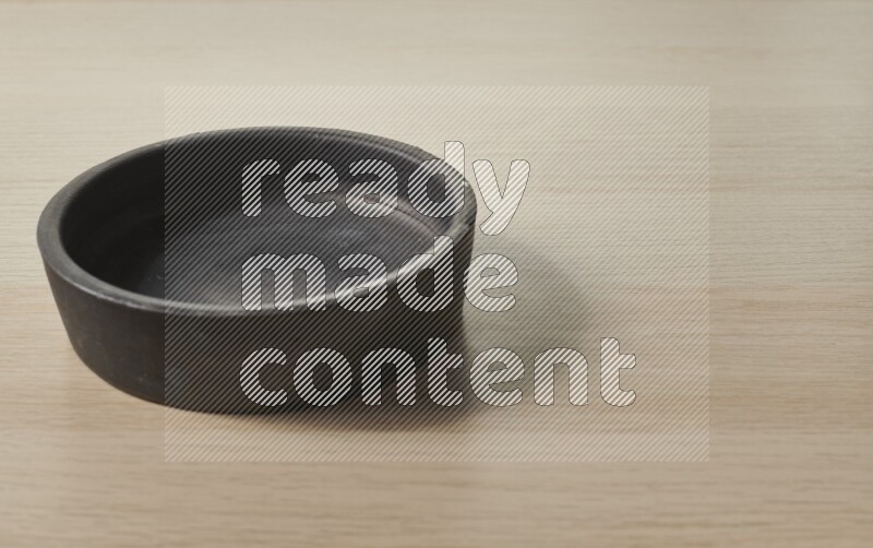 A black pottery bowl on light wooden background