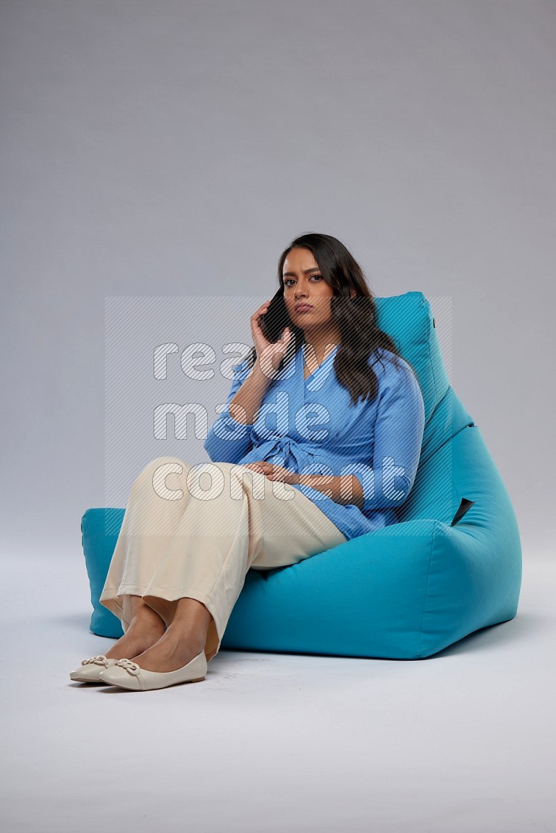 A woman sitting on a blue beanbag and talking on the phone