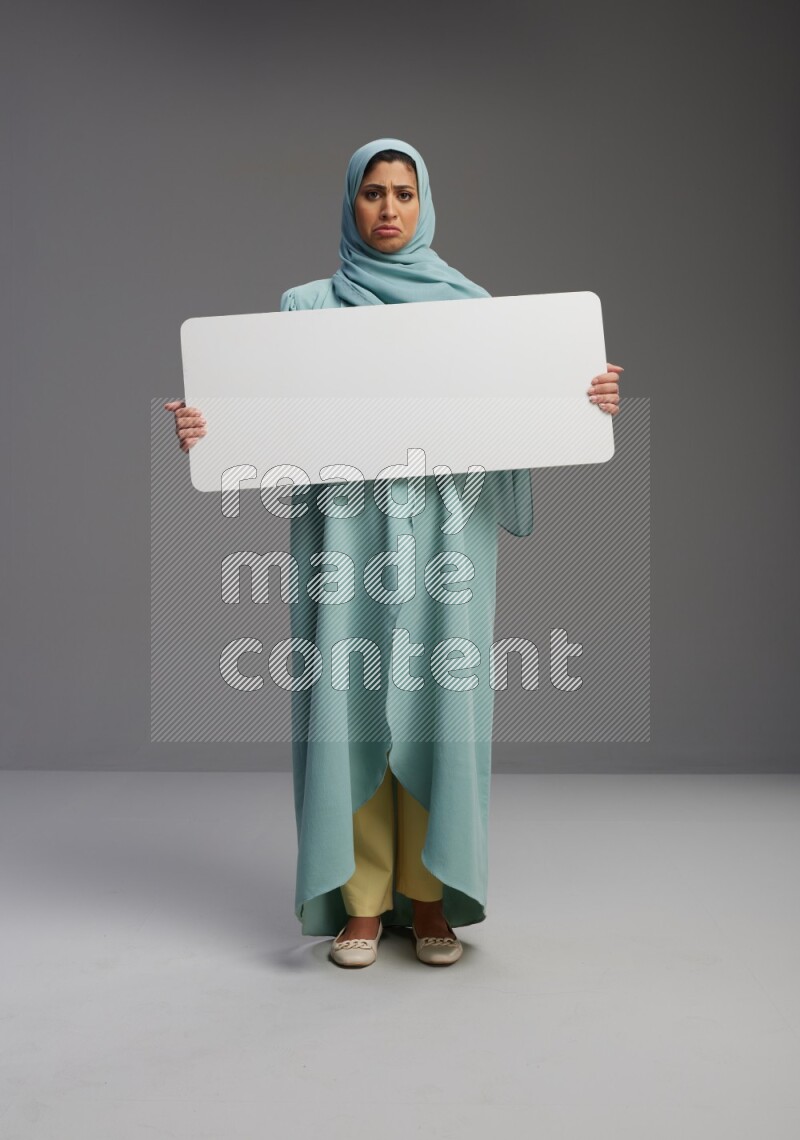 Saudi Woman wearing Abaya standing holding board on Gray background