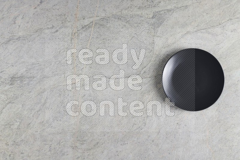 Top View Shot Of A Black Ceramic Circular Plate On Grey Marble Flooring