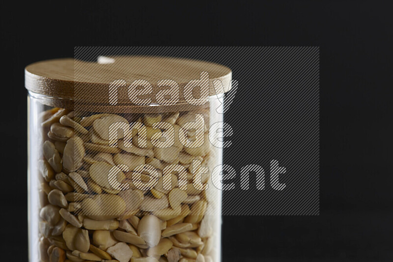 Crushed beans in a glass jar on black background