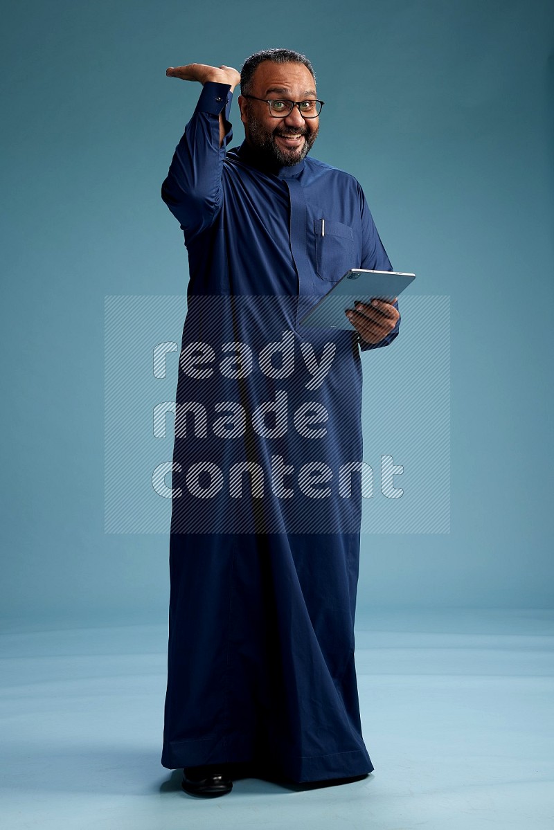 Saudi Man without shimag Standing working on tablet on blue background
