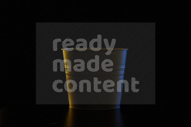 A plant pot with colored rim light against black background