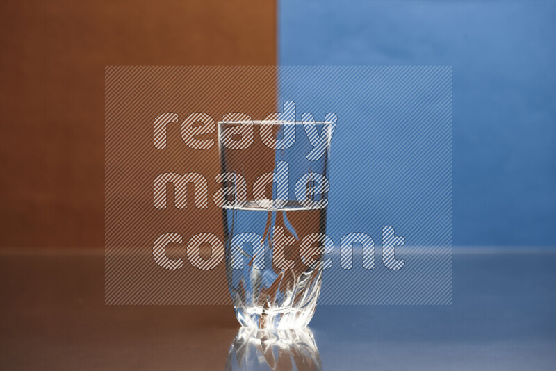 The image features a clear glassware filled with water, set against brown and blue background