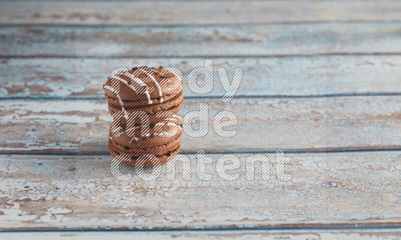 45º Shot of two Brown white  Chocolate Caramel macarons on light blue wooden background