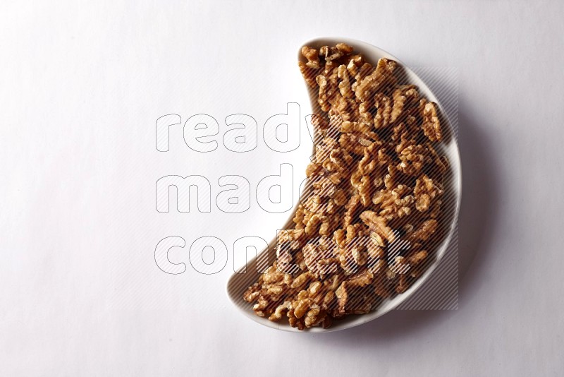 Walnuts in a crescent pottery plate on white background