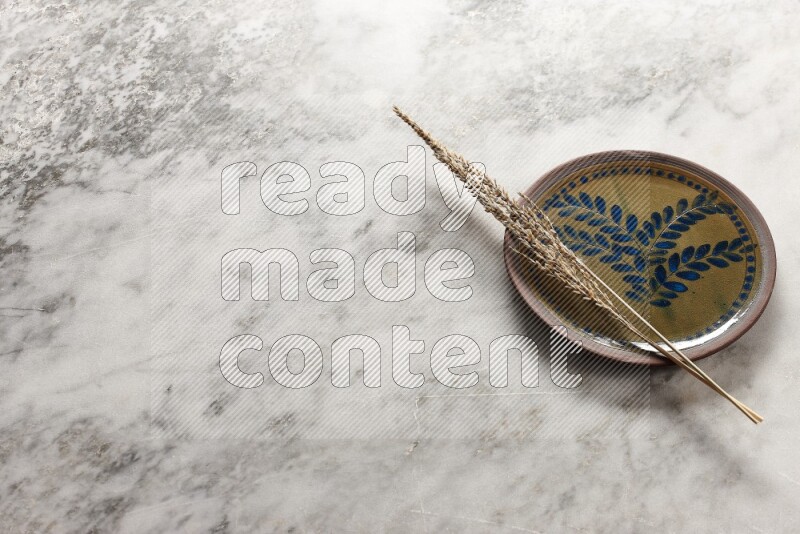Wheat stalks on decorative pottery plate on grey marble background