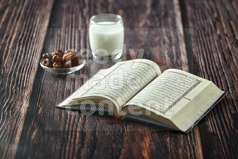 Quran with dates, prayer beads and different drinks all placed on wooden background