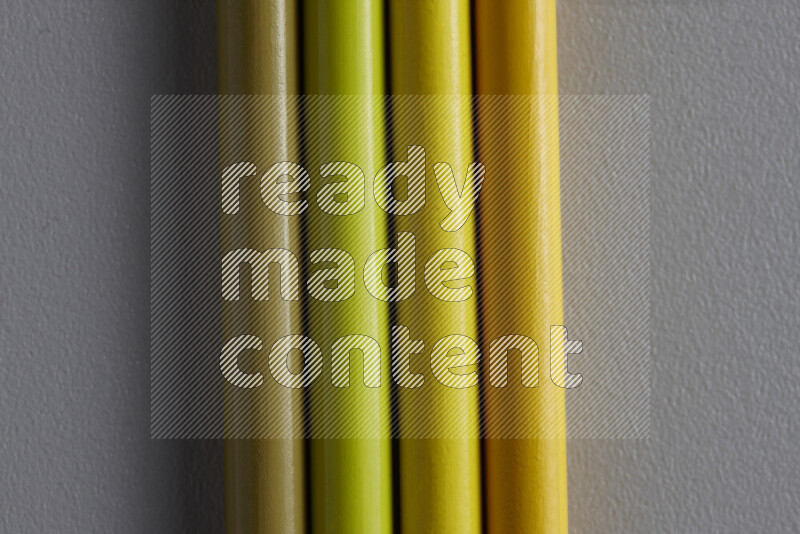 A collection of sharpened colored pencils arranged showcasing a gradient of yellow hues on grey background