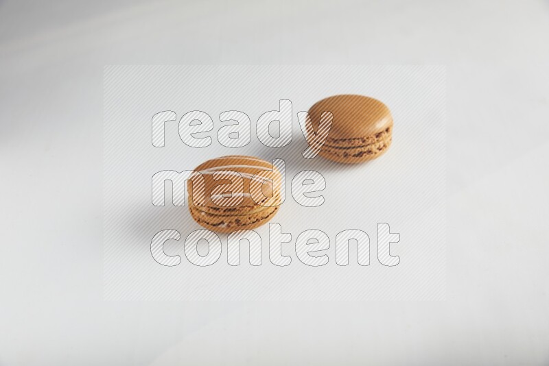 45º Shot of of two assorted Brown Irish Cream, and Brown Maple Taffy macarons  on white background