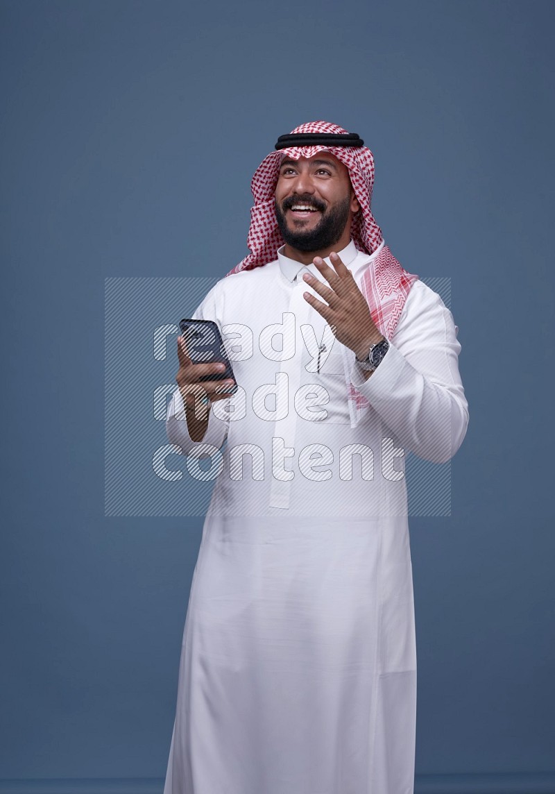 A man Texting on Blue Background wearing Saudi Thob and Shomag