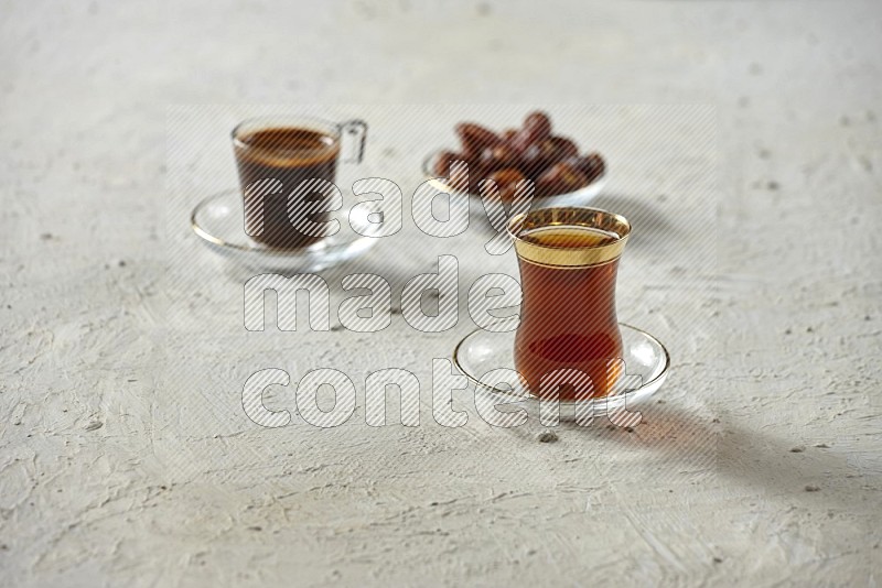 A tea glass cup with dates and coffee on textured white background