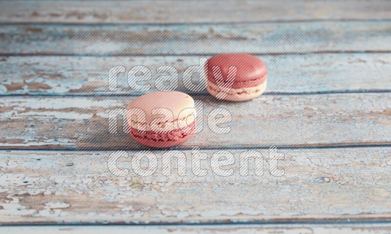 45º Shot of two Pink Litchi Raspberry macarons on light blue wooden background