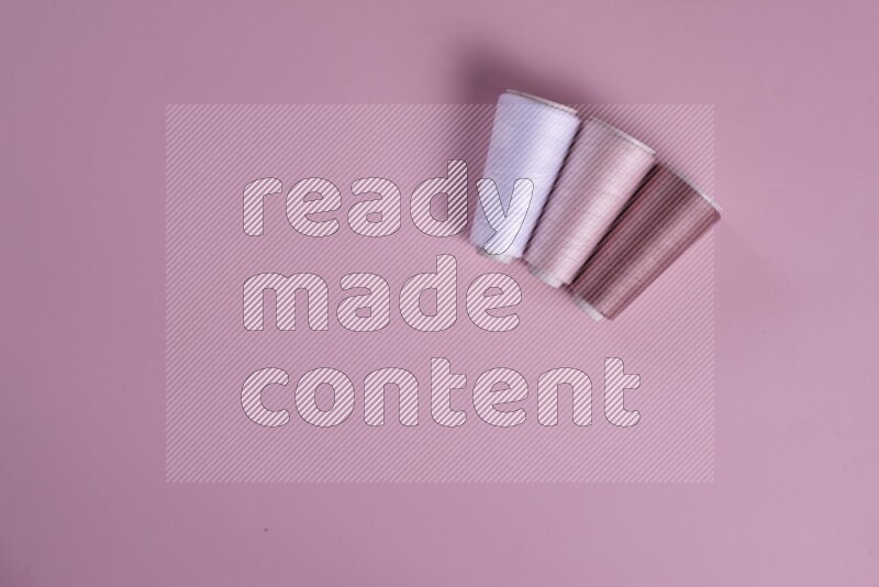 A white and pink collection of sewing and tailoring tools arranged on a pink background