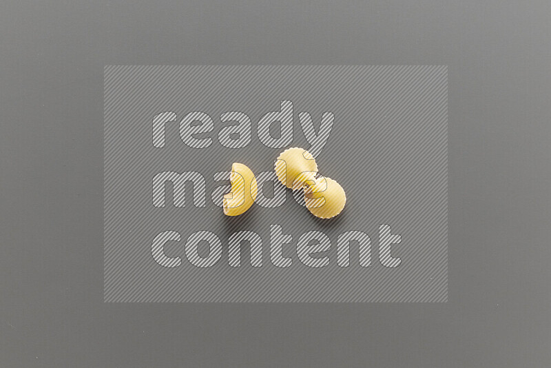 Elbow pasta with other types of pasta on grey background