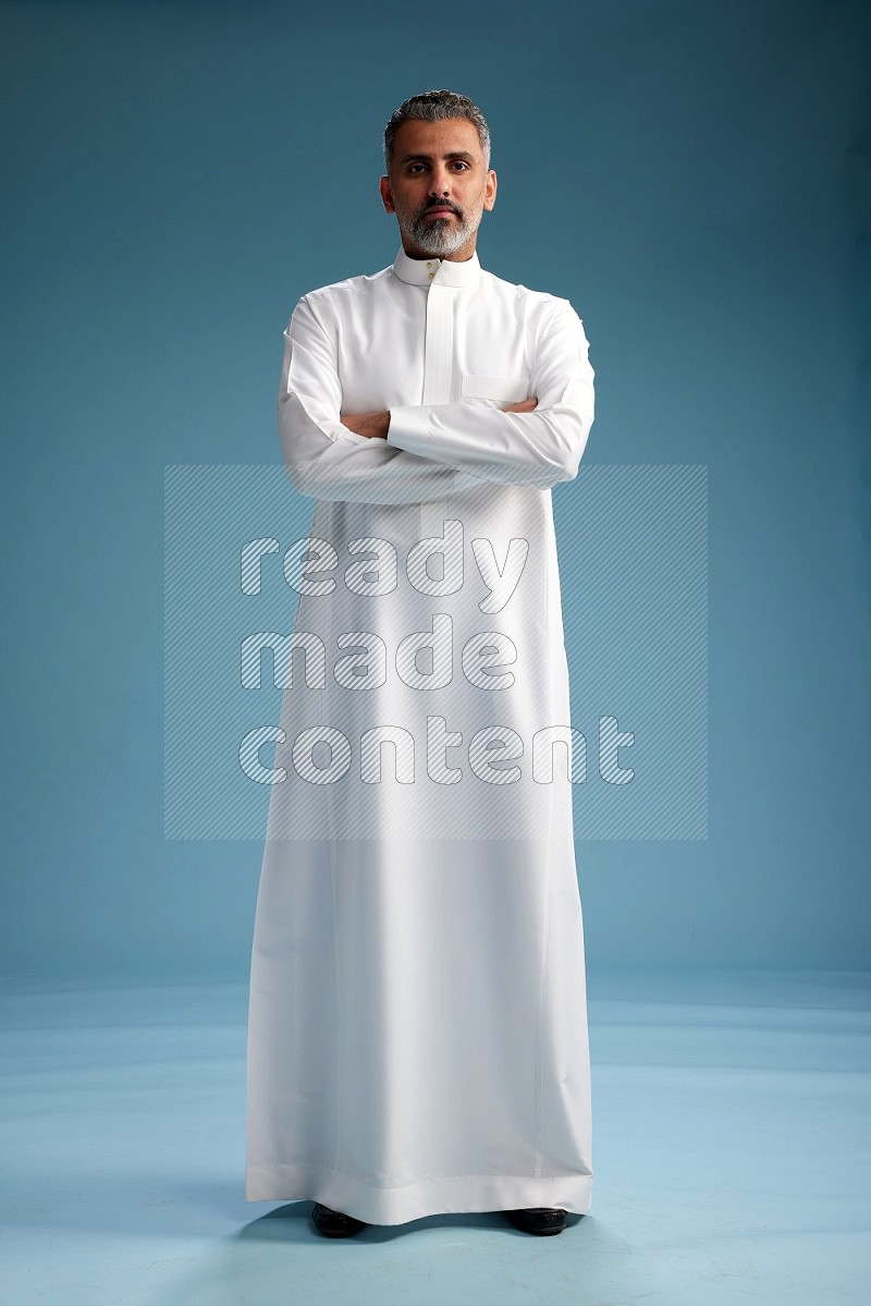 Saudi man waring thob posing to the camera on blue background