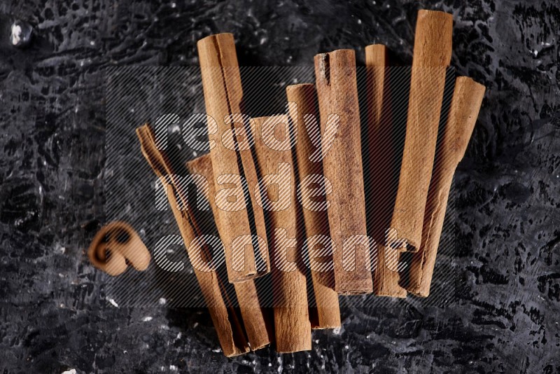 Cinnamon sticks on a textured black background