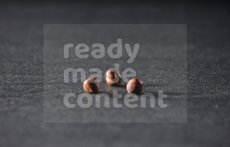 3 peeled hazelnuts on a black background in different angles