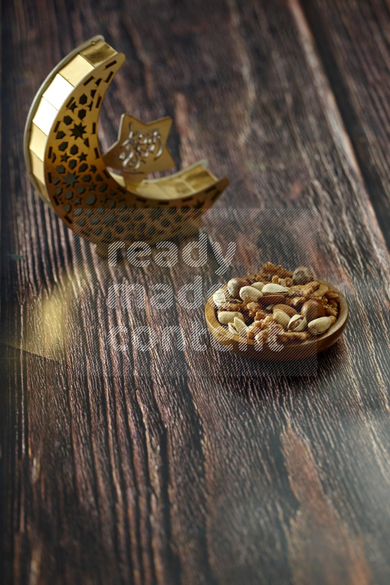 A crescent lantern with drinks, dates, nuts, prayer beads and quran on brown wooden background