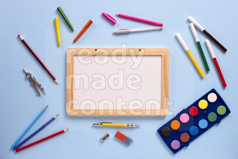 A white board with school supplies on blue background (back to school)