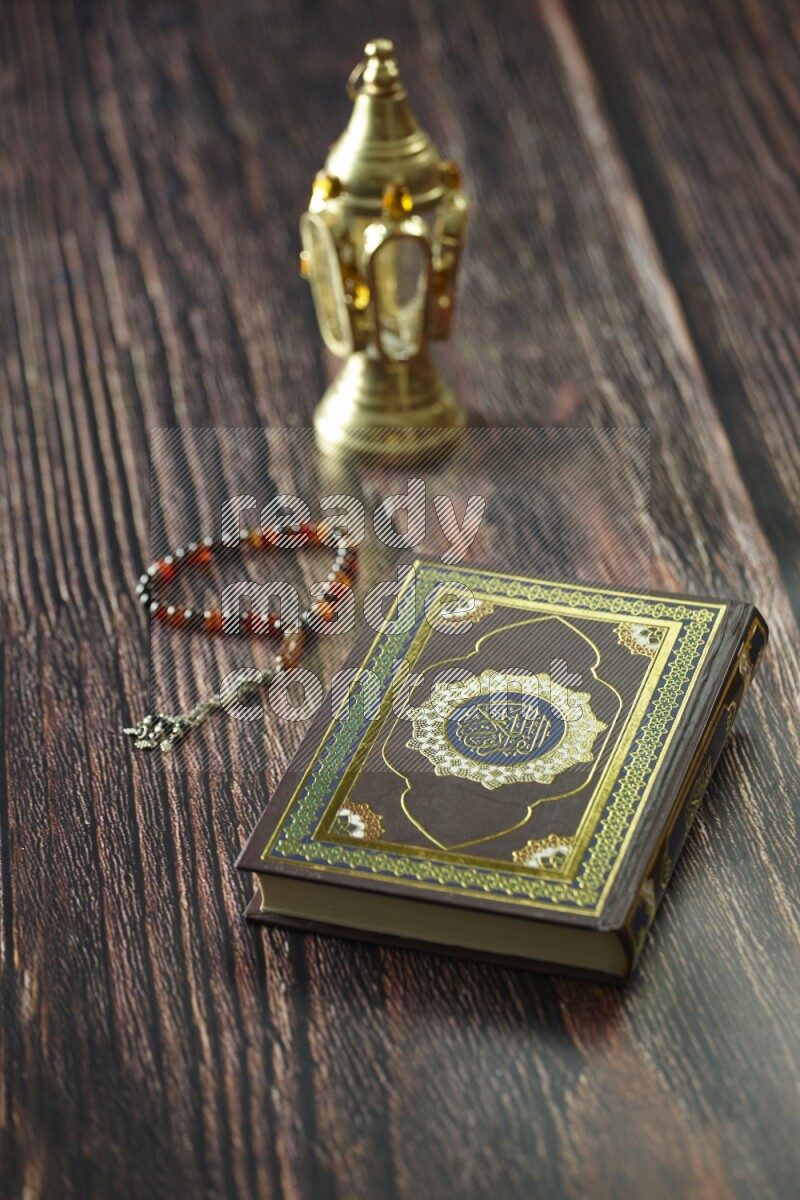 A golden lantern with different drinks, dates, nuts, prayer beads and quran on brown wooden background