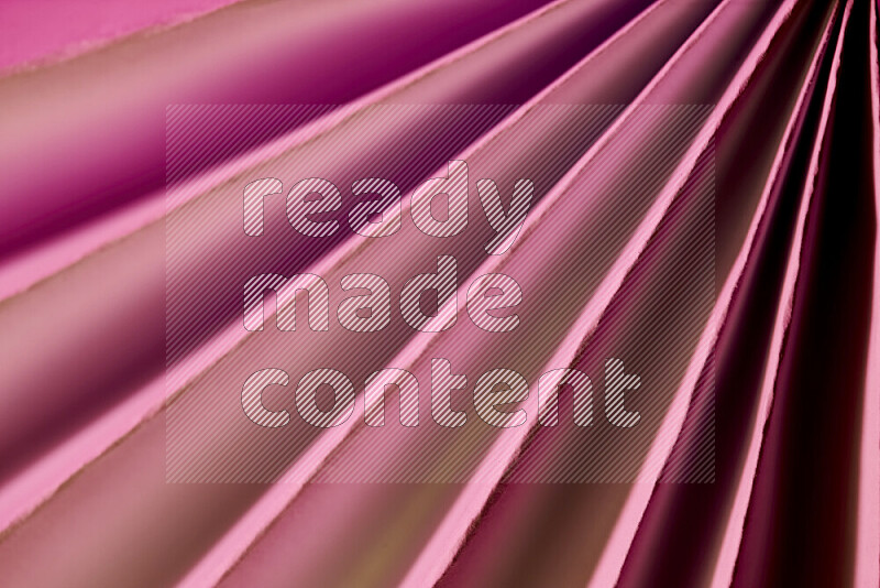 An image presenting an abstract paper pattern of lines in pink and gold tones
