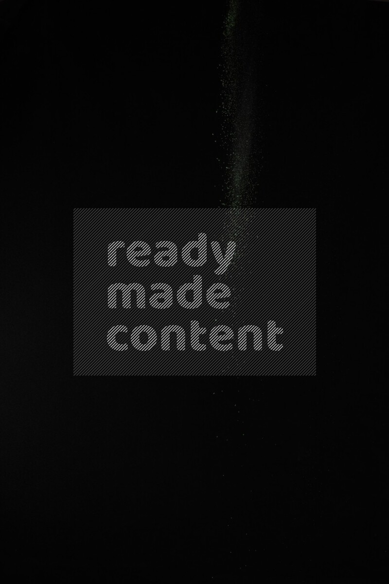 A side view of green powder explosion on black background