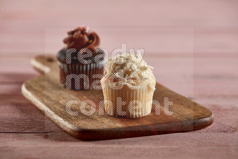 Vanilla mini cupcake topped with coconut on a wooden board