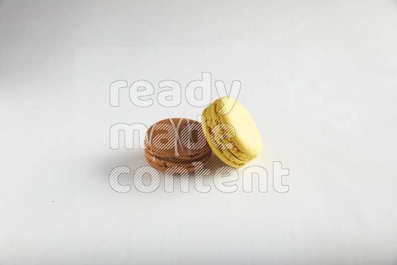 45º Shot of of two assorted Brown Irish Cream, and Yellow Lemon macarons on white background