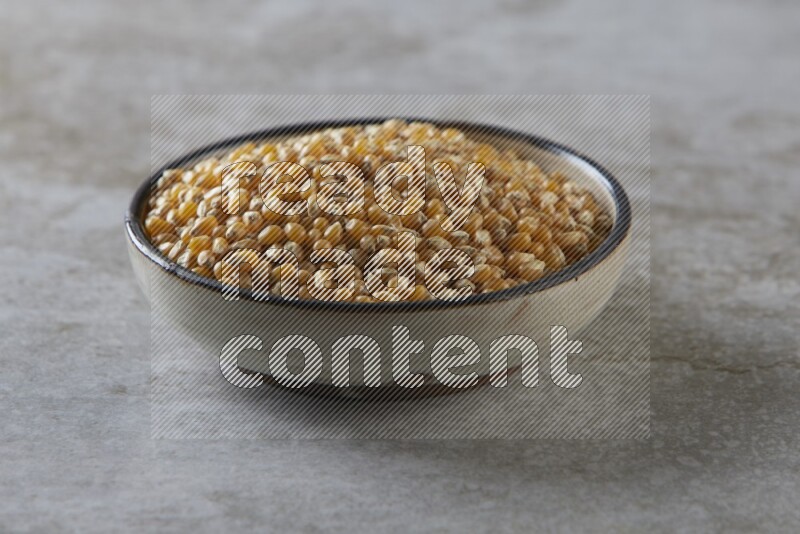 corn kernel in a multi-colored pottery bowl on a grey textured countertop